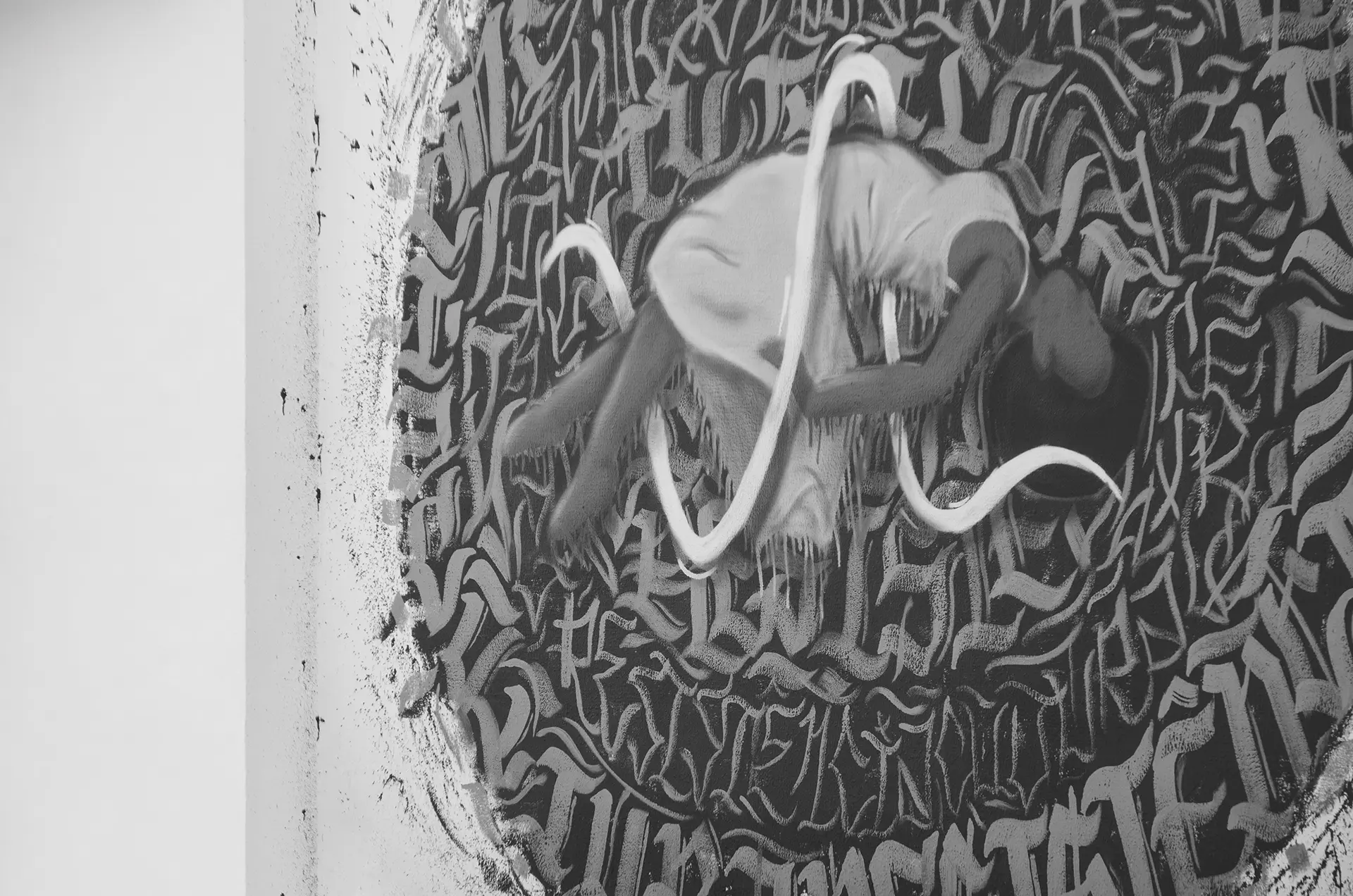Fotografia em tons de cinza de um mural de graffiti com uma mulher flutuando ao centro